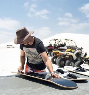 Muž drží skateboard vedle skupiny surfových prken