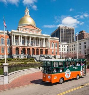 an orange trolley driving down a street in front of a building