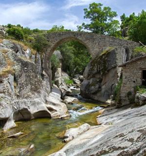 an old stone bridge over a river with rocks