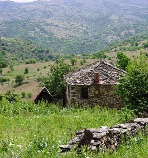 an old house in a field with a stone wall