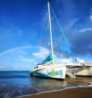 一艘船停在沙滩上，背景是彩虹