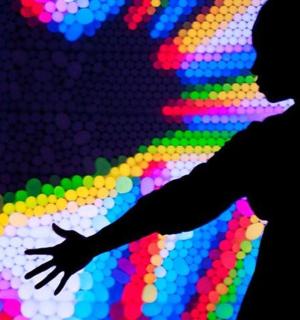 a silhouette of a man standing in front of a colorful wall