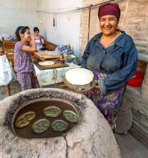 一位女士站在厨房里,厨房里有一个石炉