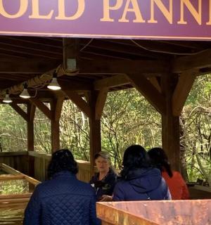 Skupina lidí stojí u cedule s nápisem „rýžování zlata“