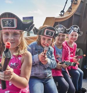 a group of girls singing into a microphone on a pirate ship