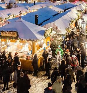 a crowd of people walking around a christmas market