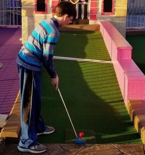 一个小男孩在假高尔夫球场打高尔夫球