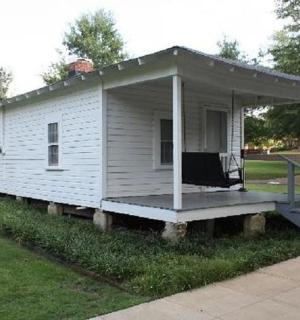 a small white house with a porch on the grass