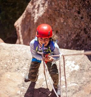 一个戴着红色头盔的小女孩在攀爬岩石