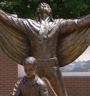 a statue of a boy standing in front of a statue