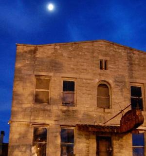 an old brick building with the moon in the sky