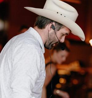 a man wearing a cowboy hat talking on the phone