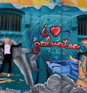 一位女士站在壁画墙前