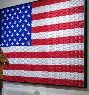 a man talking on a cell phone in front of an american flag painting