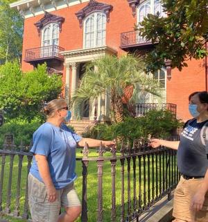 two men standing in front of a fence in front of a house