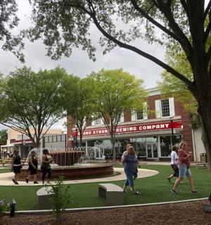 lidé procházející se parkem před budovou