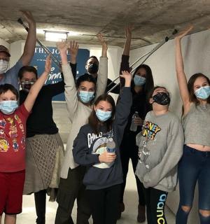 skupina lidí stojících v místnosti s rukama ve vzduchu