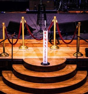 一个舞台，上面有一张木桌，上面有一块牌子