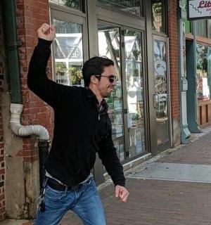 muž jdoucí po ulici s rukou ve vzduchu