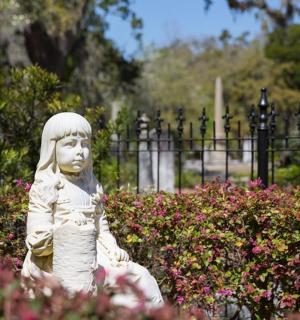 a statue of a little girl sitting in a garden