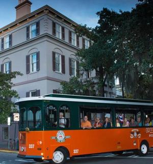 an orange and green bus driving down a street
