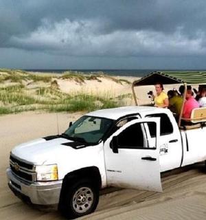 skupina lidí jedoucích v zadní části bílého nákladního auta