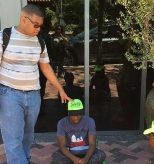 一名戴着绿帽子的男子站在一名男孩的身上