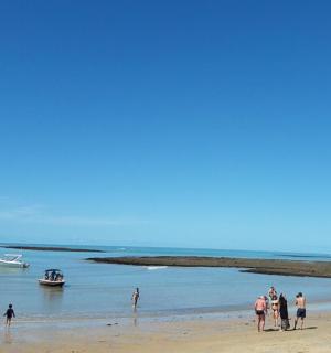 一群人在海滩上，水里有船