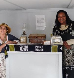 两个女人站在桌子后面，手里拿着一瓶威士忌