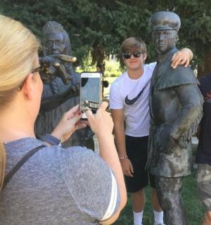 žena fotografující sochu dvou mužů