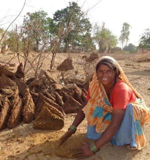 a woman sitting on the ground next to a pile of rocks