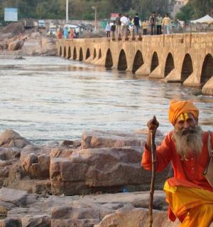 a man sitting on the rocks next to a river