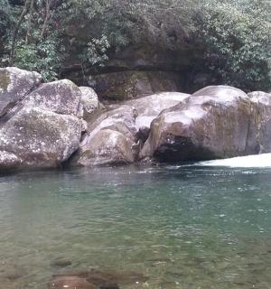 osoba stojící ve vodě vedle vodopádu