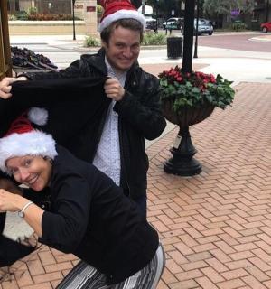 two people dressed in santa hats standing on a sidewalk