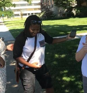 three women standing in a park with a cell phone