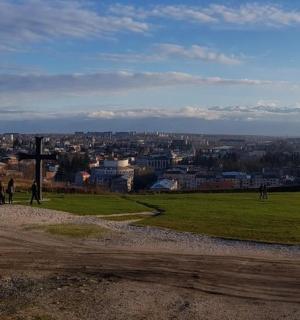 two people standing on a hill looking at a city
