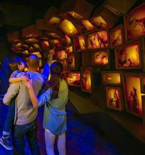 skupina lidí stojících před zdí s obrazy