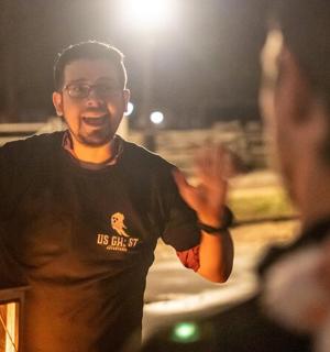 Muž stojí v noci vedle lucerny