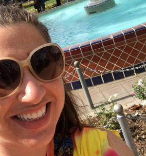 a woman wearing sunglasses standing next to a swimming pool