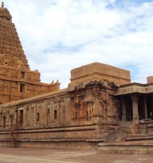 一座巨大的石头建筑，背景是一座塔