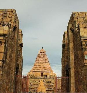 一座巨大的石头建筑，背景是一座塔