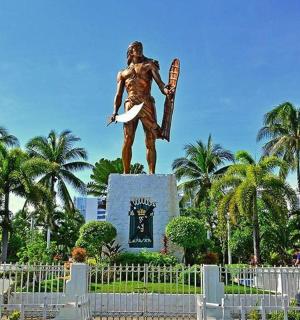 uma estátua de um homem segurando uma prancha de surfe