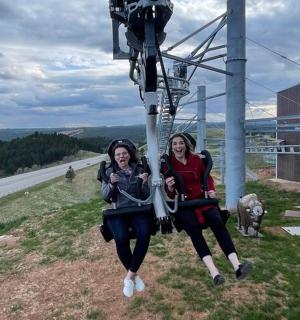 two women are sitting on a ski lift