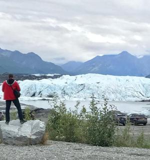 a person standing on a rock in front of a glacier
