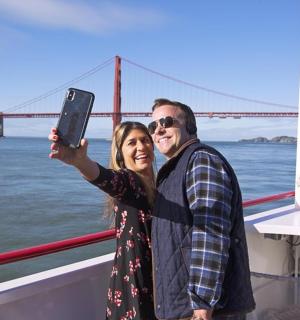 a man and woman standing on a boat in front of a bridge