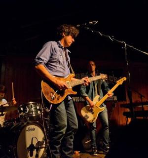 skupina lidí hrajících na kytary na pódiu