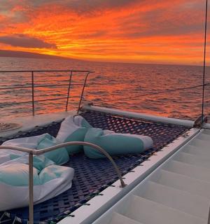 a deck of a boat in the ocean with a sunset