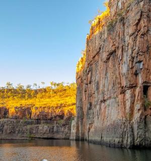 a large rock wall next to a body of water