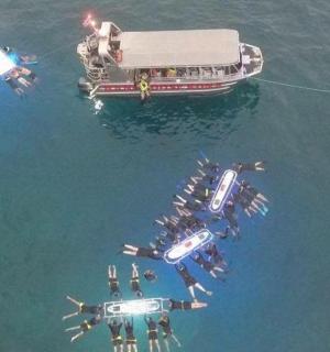 skupina lidí ve vodě vedle lodi