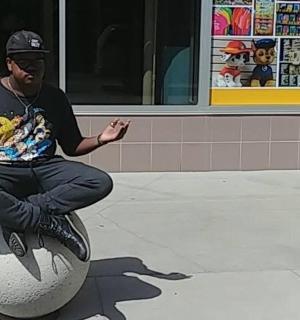 muž sedící na míči před obchodem